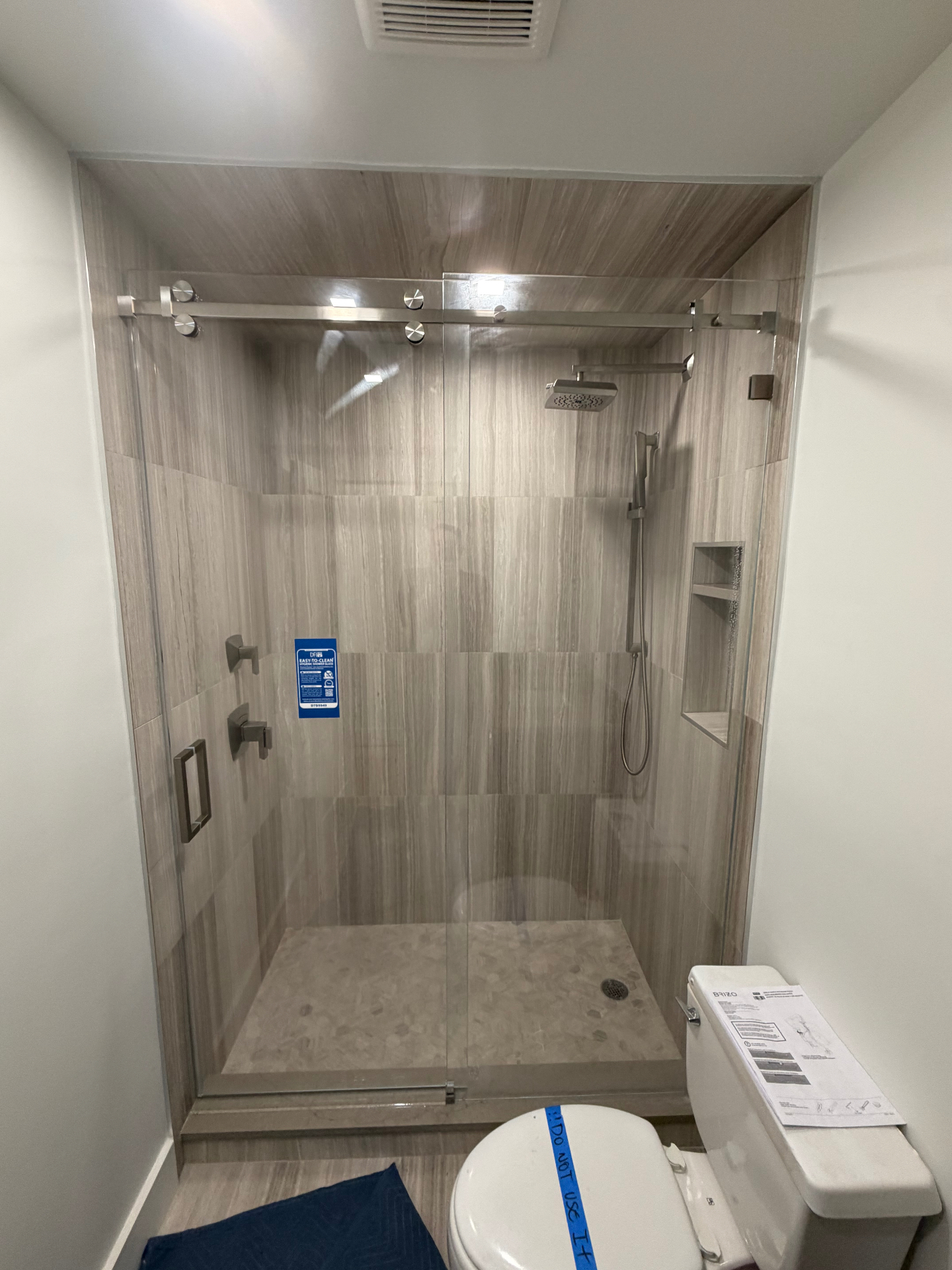 Sliding glass shower door with stainless steel barn-style hardware — Fort Myers install