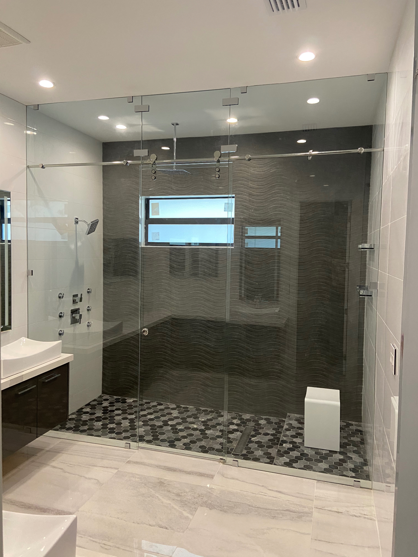 Frameless sliding shower enclosure with chrome hardware and dark wave tile — Cape Coral install